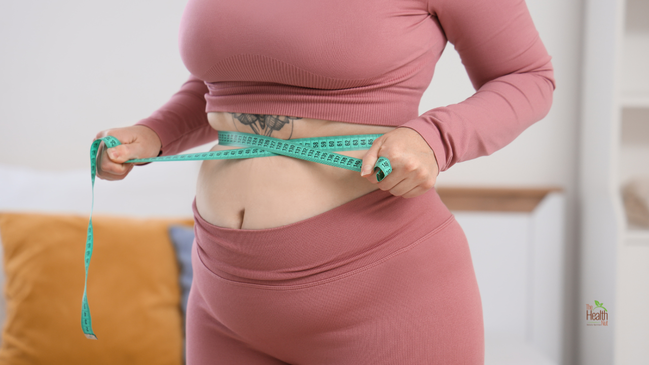 Woman in workout clothes taking her measurements with a large belly