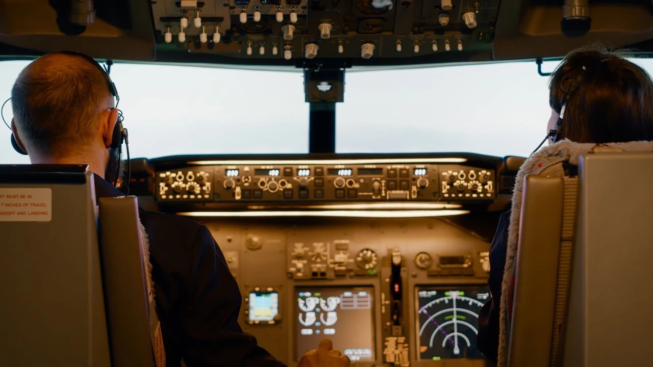 Two pilots in a commercial aircraft cockpit, representing the importance of communication, shared awareness, and team decision-making under pressure.