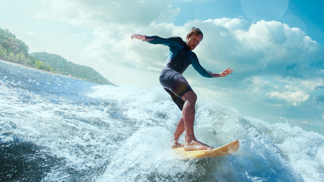 A surfer balancing on a large wave—symbolising emotional mastery, balance, and adaptability.
