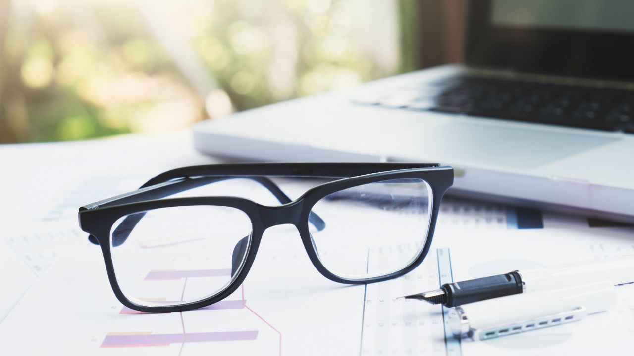image of a pair of spectacles resting on a performance report to represent the "lens" of our assumptions