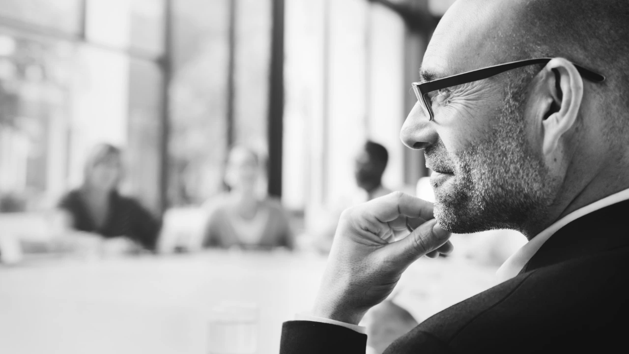 Leader pausing to reflect before speaking with team — symbolising emotional intelligence and high-performance leadership.