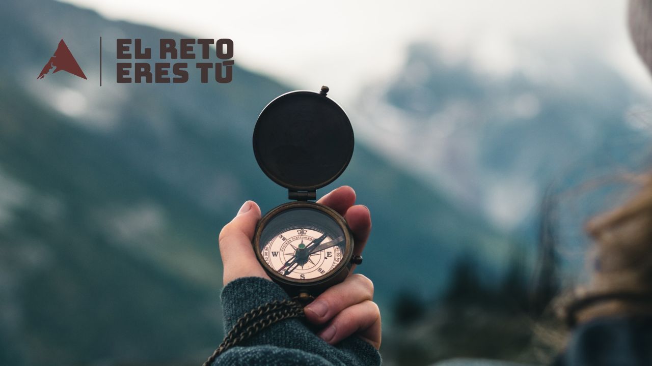 Corredor de ultra trail sosteniendo brújula en montaña para orientarse antes de elegir objetivo