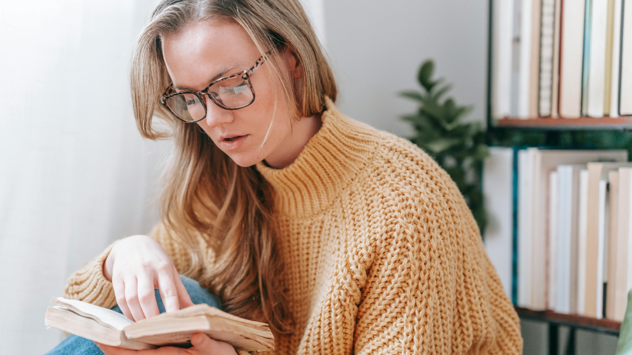 Woman reading quietly in soft natural light, reflecting with faith during a season of financial overwhelm