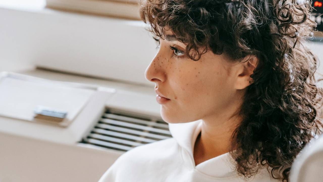 A woman sitting by a window reading quietly in soft natural light, reflecting during an overwhelming season and finding gentle hope.