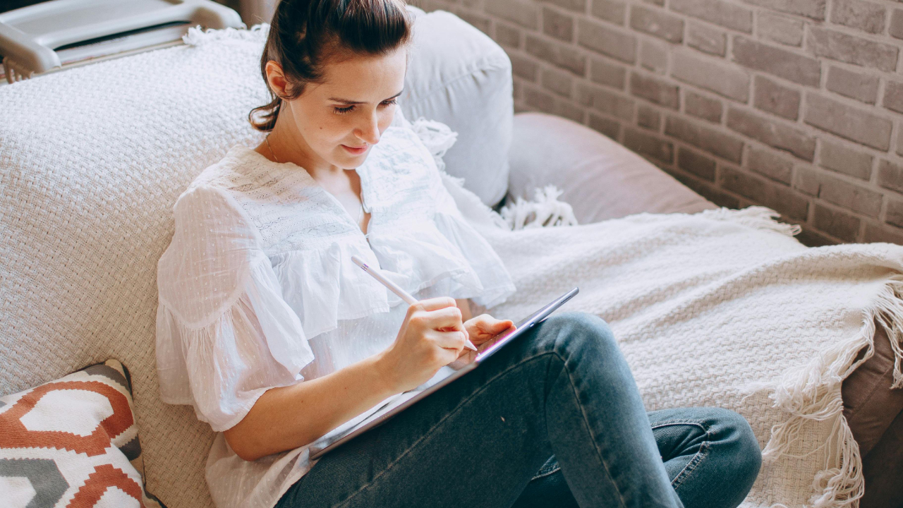 Woman journaling quietly on a couch in soft natural light, reflecting and reclaiming hope during a financial reset