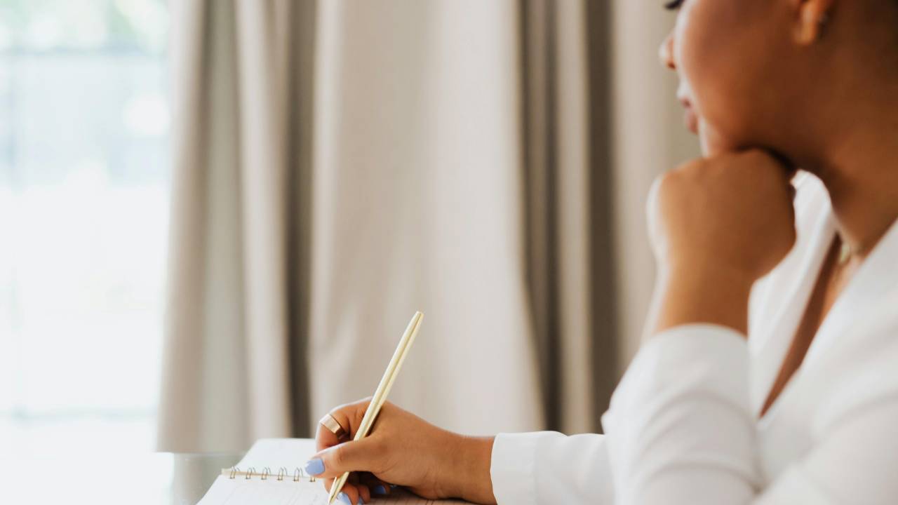 Woman journaling at a desk as she rebuilds confidence after a financial crisis