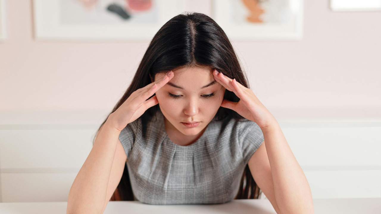 Woman sitting at a table with journal and phone, reflecting quietly during a difficult financial season