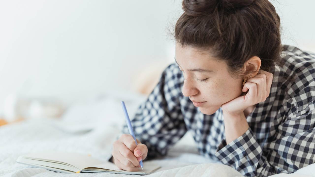 Woman journaling quietly in a calm, cozy space as part of a peaceful weekly reset for mind and money