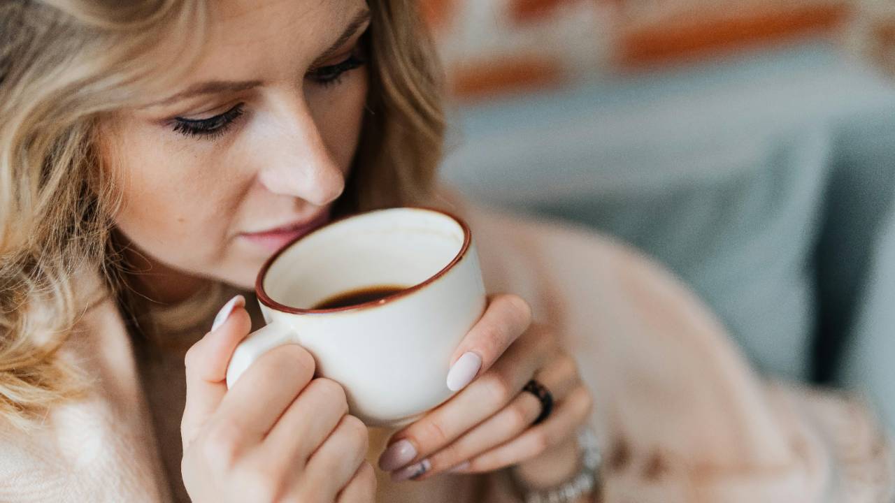 Woman holding a warm cup of coffee during a quiet moment of reflection after financial hardship