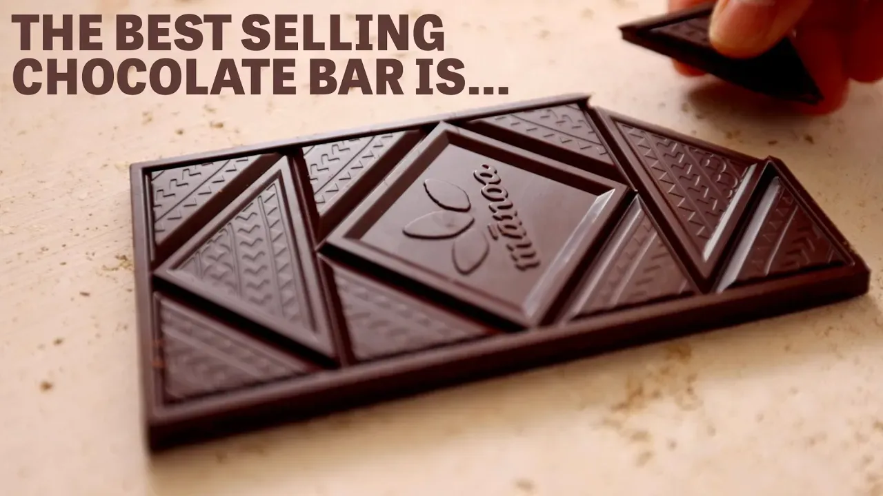 Image of a hand grabbing a piece of a chocolate bar with text reading "The Best Selling Chocolate Bar Is".