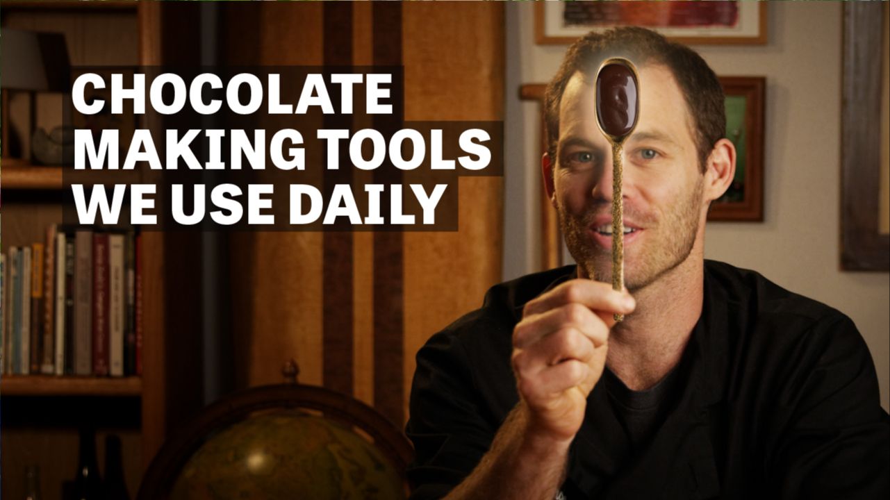 Image of a man holding a spoon with chocolate with text reading "Chocolate Making Tools We Use Daily". 