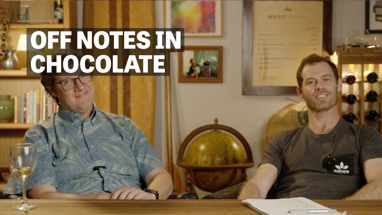 Image of two men sitting at table with text reading "Off Notes In Chocolate". 