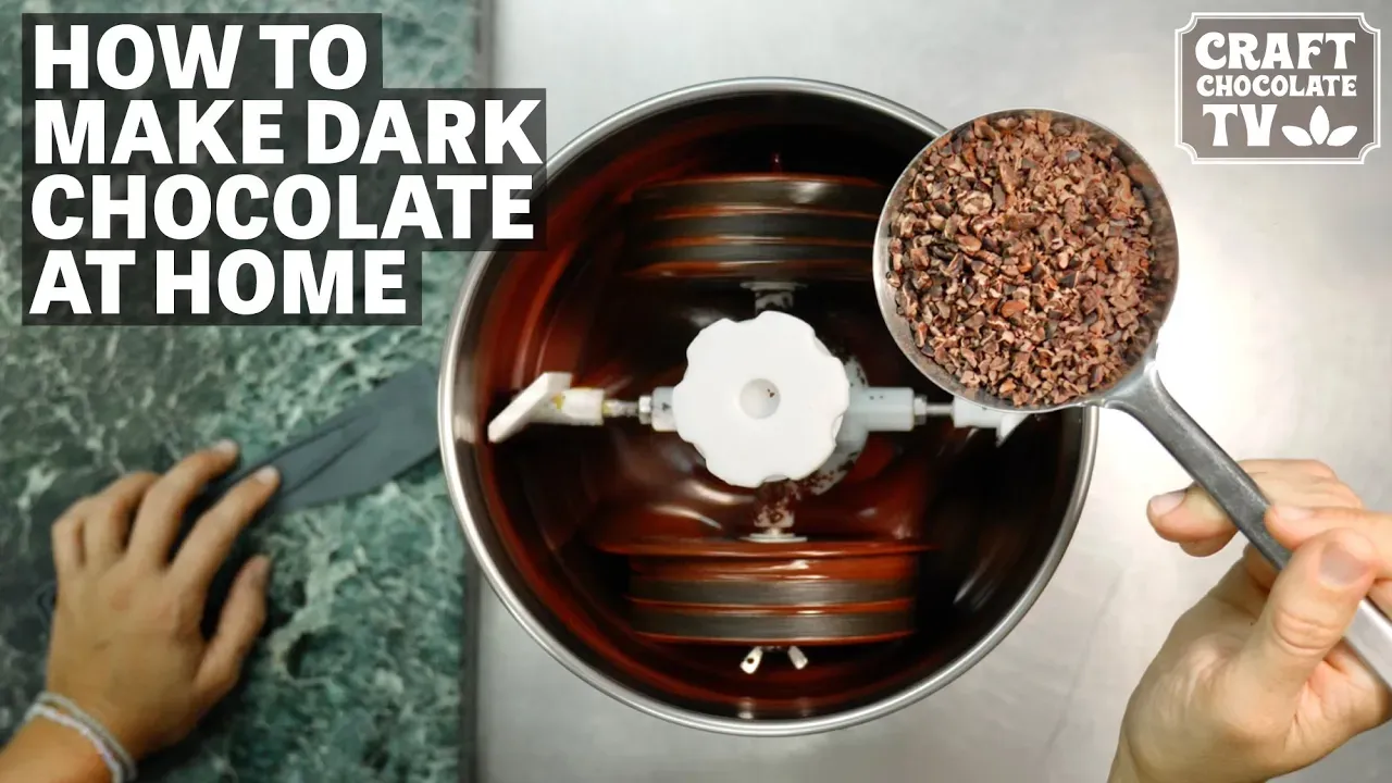 Image of a mini chocolate grinder with a hand holding a scoop of cacao nibs over it with text reading "How To Makde Dark Chocolate At Home"