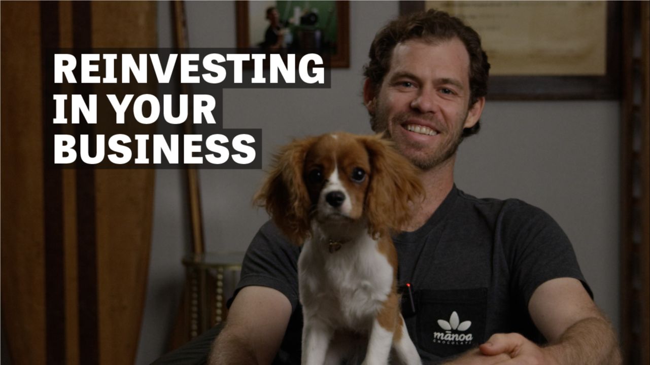 Image of a man sitting with a dog with text reading "Reinvesting in your business". 