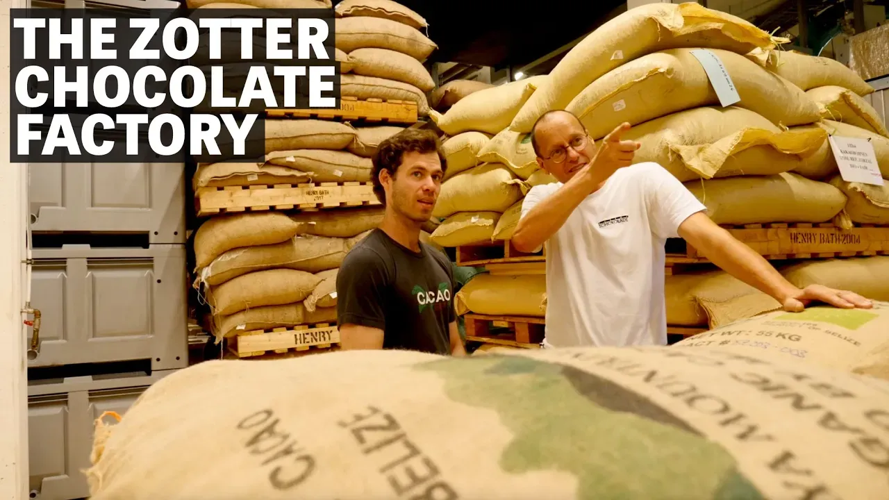 Image of two men talking around cacao sacks with text reading "The Zotter Chocolate Factory". 