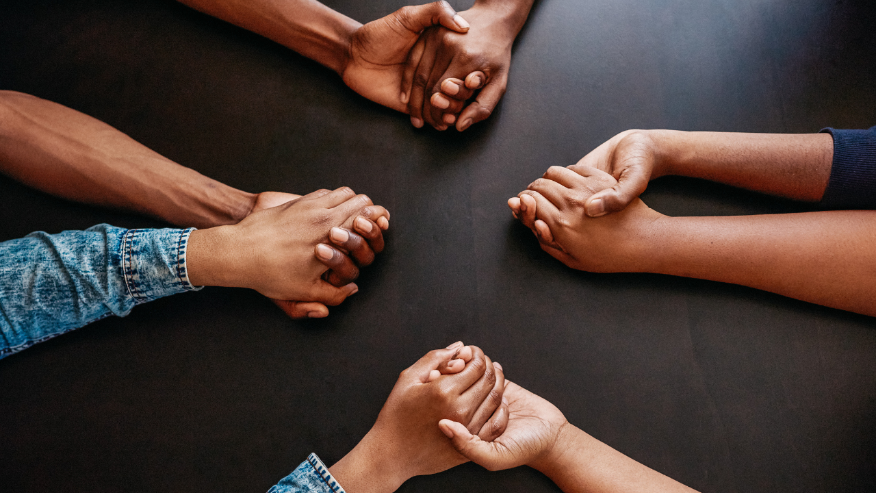 People holding hands while being seated at a table