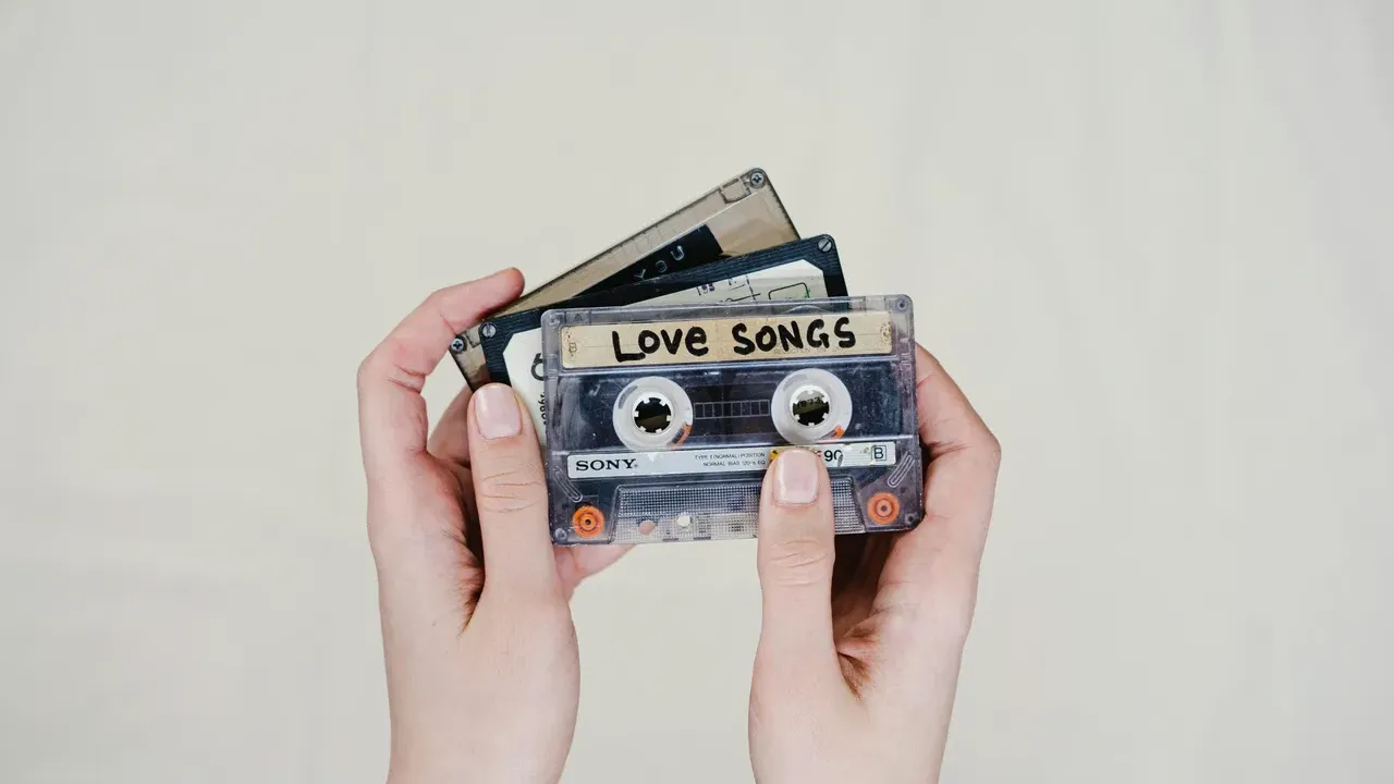 Hands holding mixed tapes with the top labeled, "love songs"