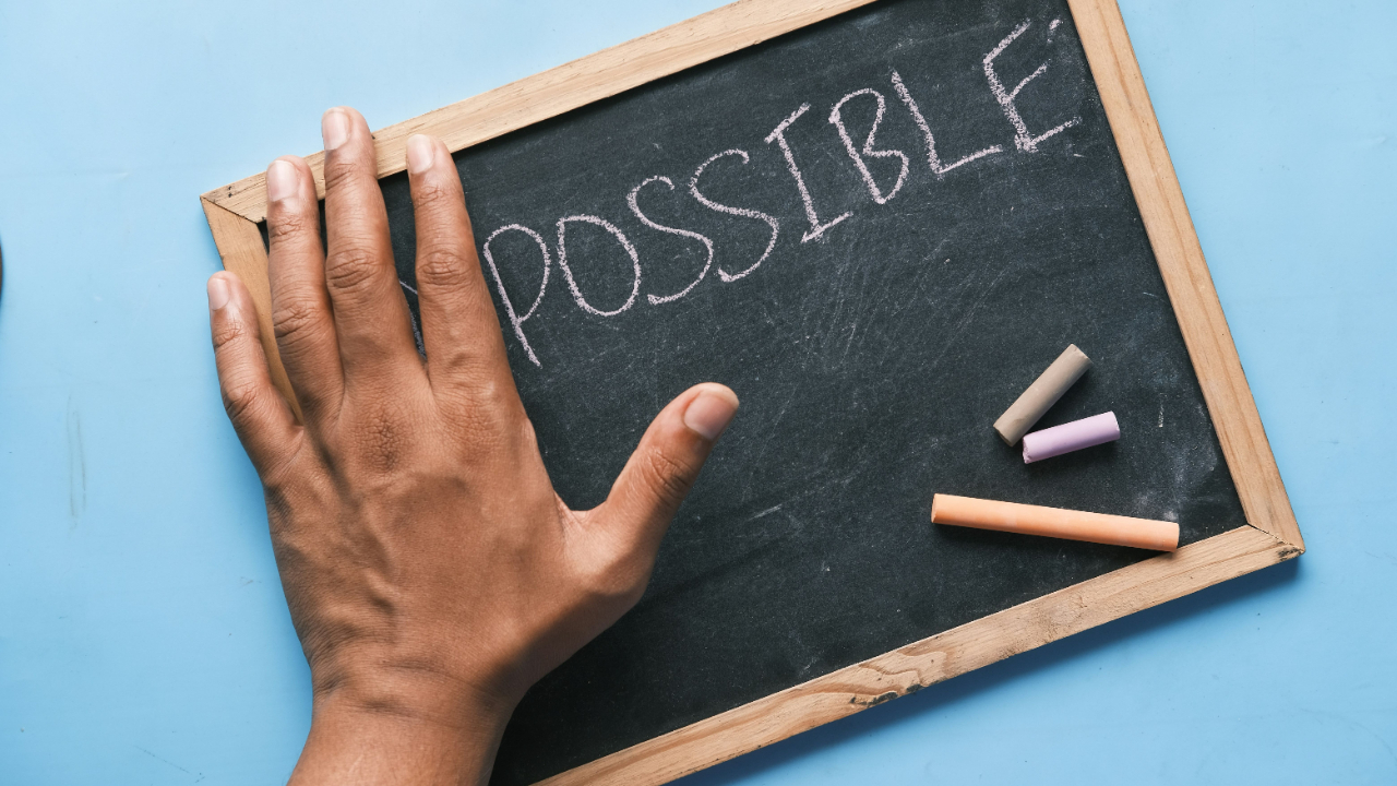 chalkboard with the word possible written on it, a hand covers where it would say 'impossible'