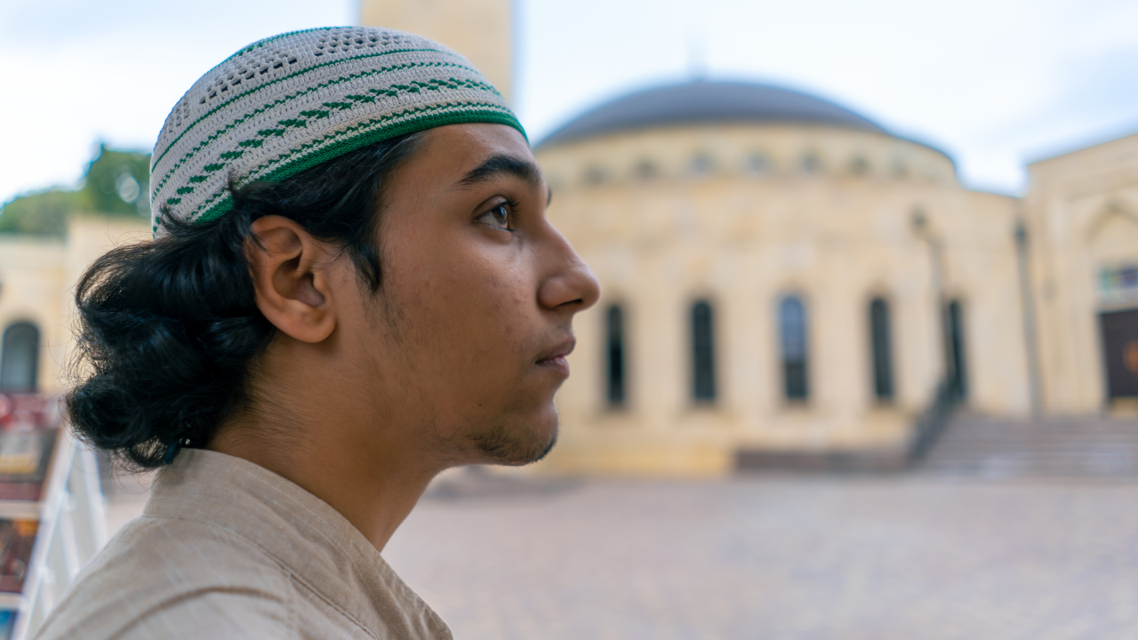 Young man looking at a mosque, warning traditional clothing.