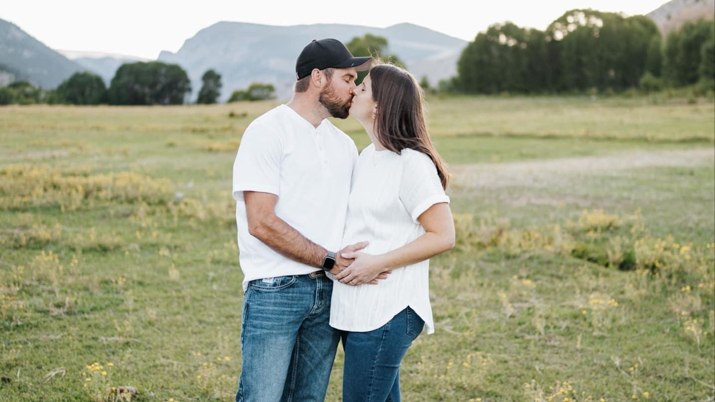 expectant-couple-kissing-in-open-field