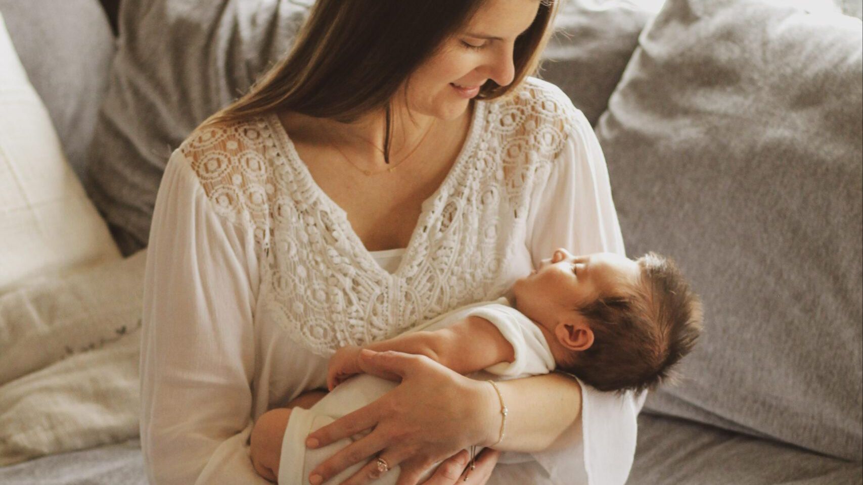 mother-holding-newborn-baby-on-sofa