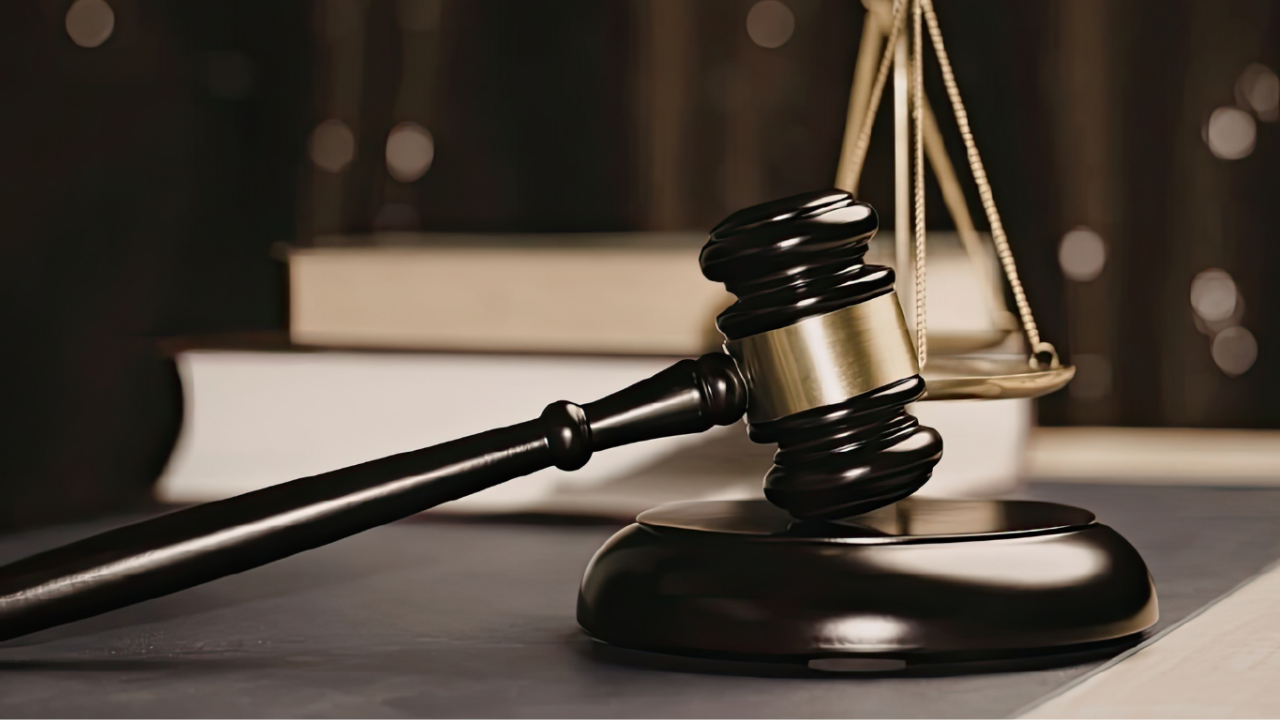 Martelletto del giudice con bilancia della giustizia e codici di legge, simbolo dei reati presupposto del D.Lgs. 231/2001