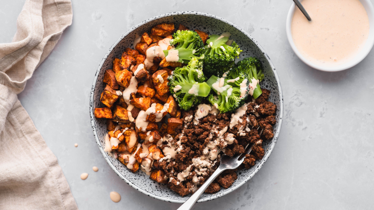 Bowl med kjøttdeig, søtpotet og brokkoli servert med dressing
