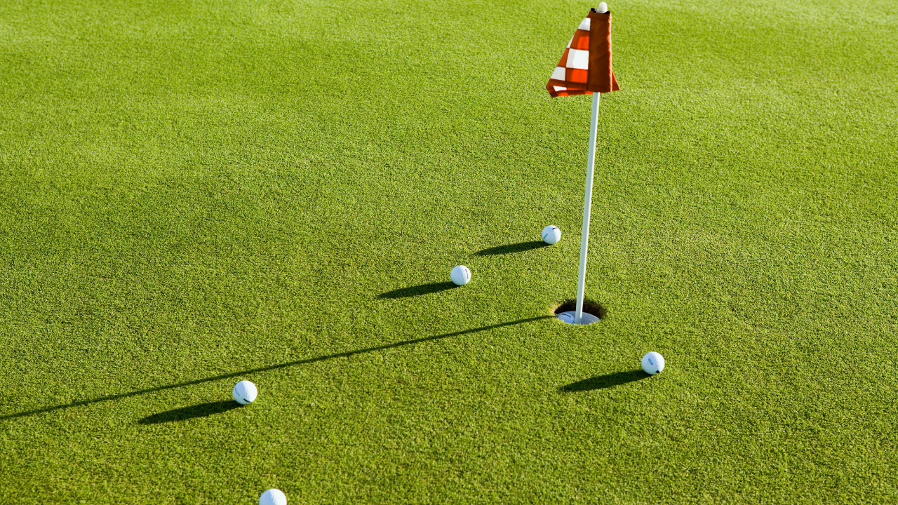multiple golf balls around the hole on the green.