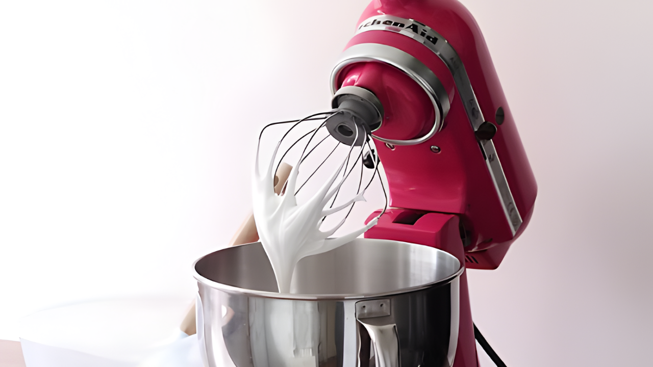 Red KitchenAid stand mixer with whisk attachment making Swiss meringue buttercream