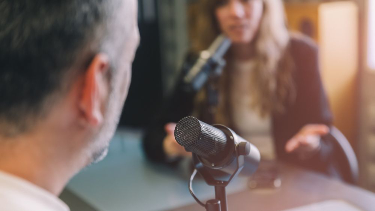 Person being interviewed on a podcast or media recording, speaking into a microphone during a live conversation