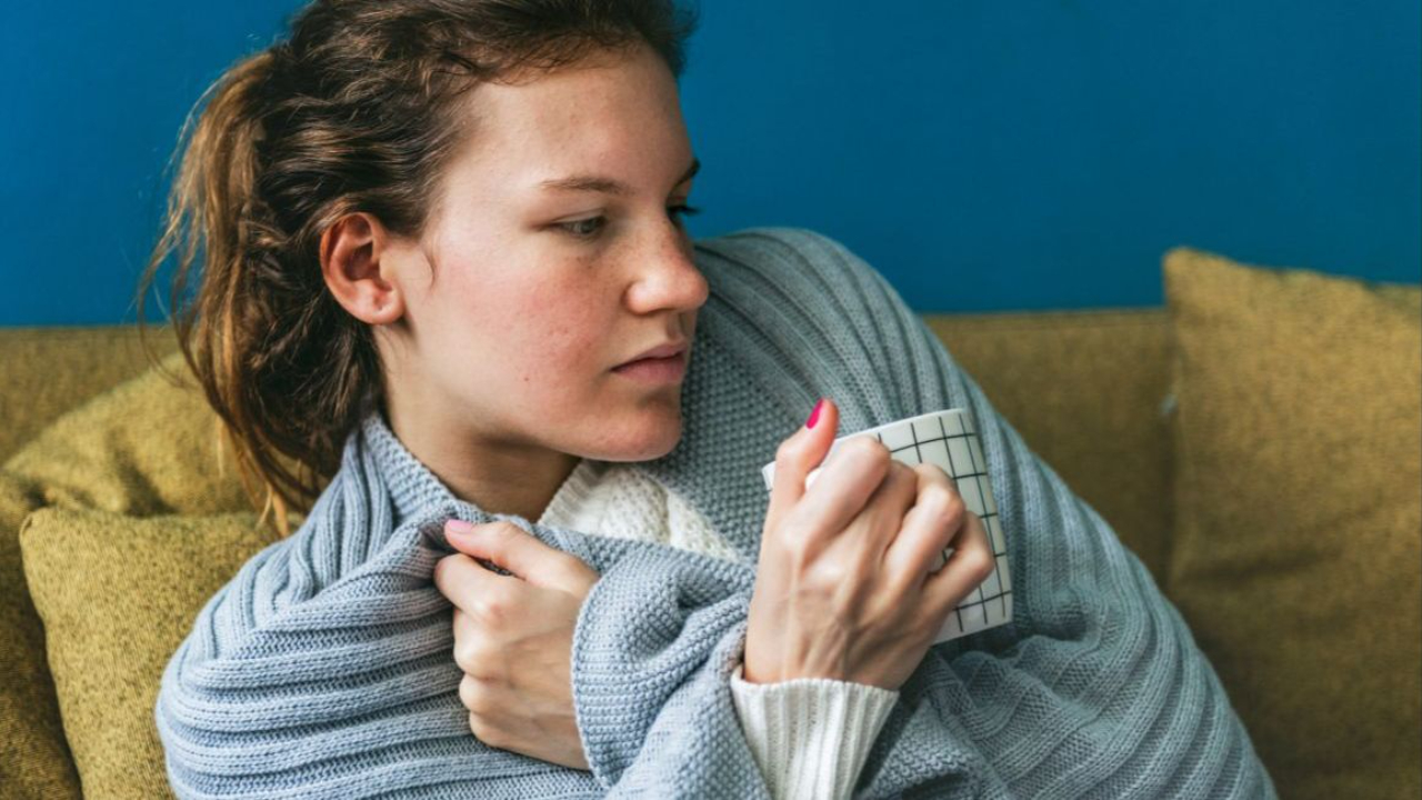 Woman in blanket drinking tea, sad