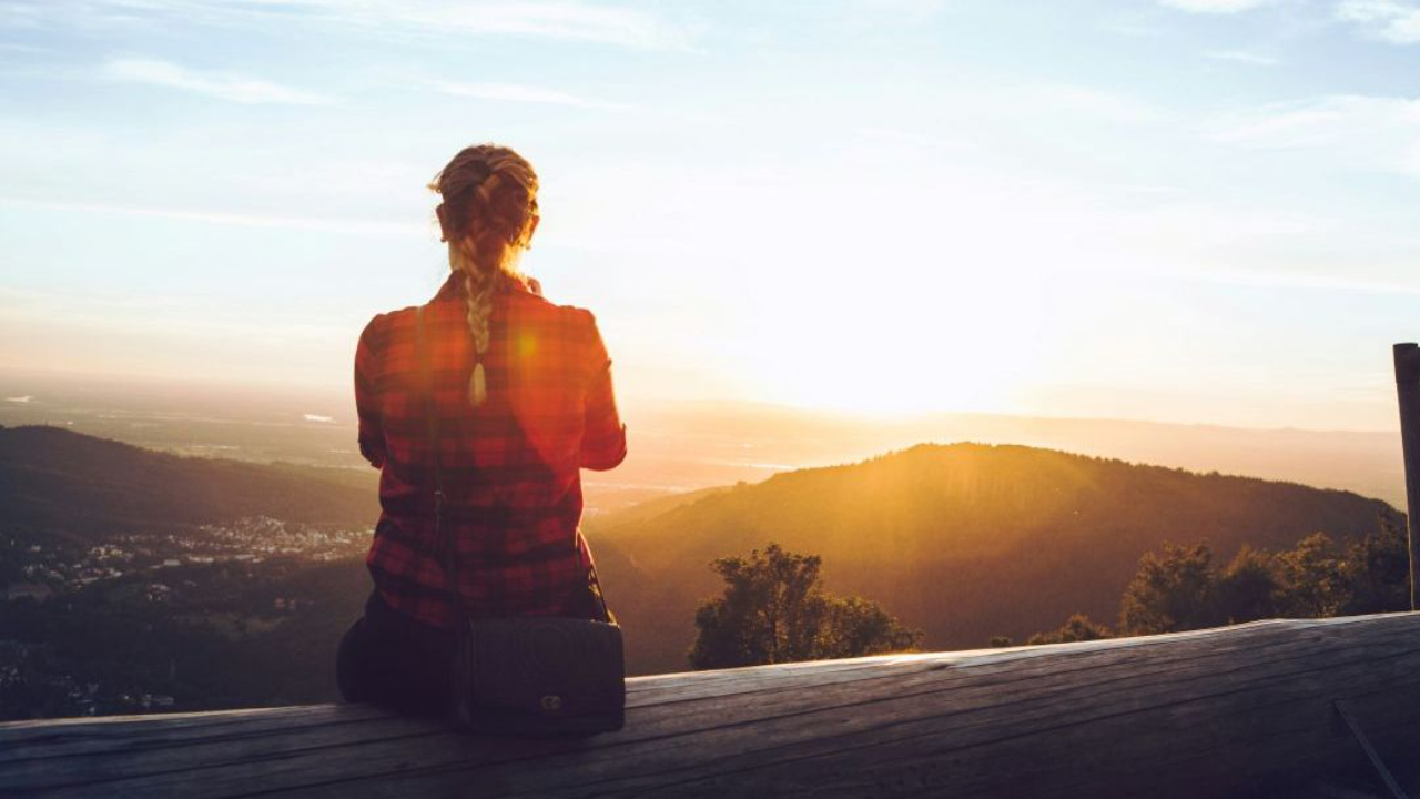Woman looking out at valley at sunrise