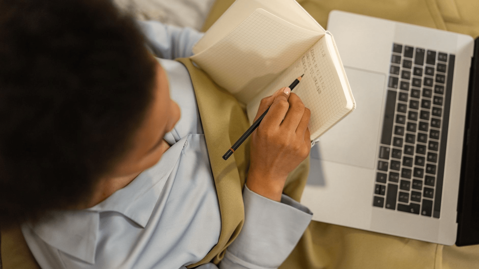 woman writing on a notebook and laptop