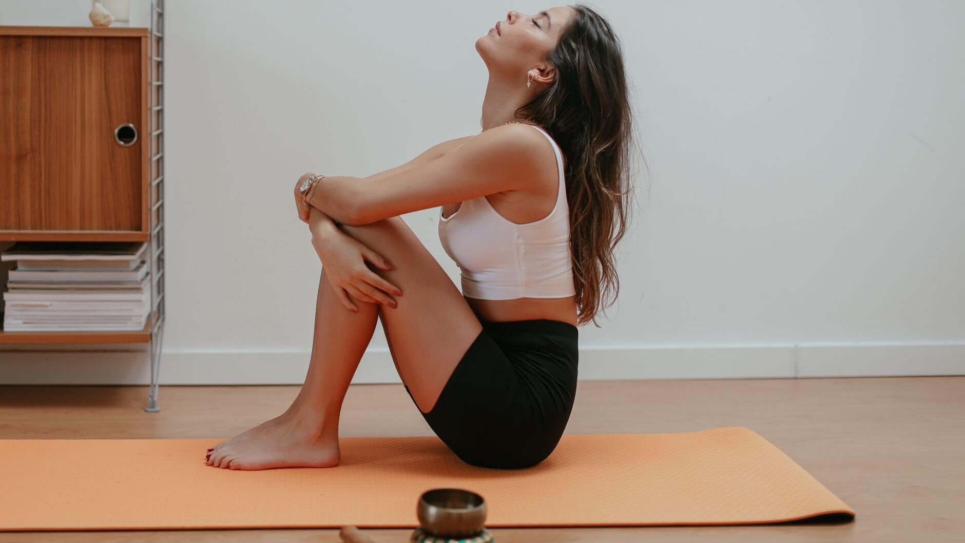 a woman in a crouching position over a yoga mat