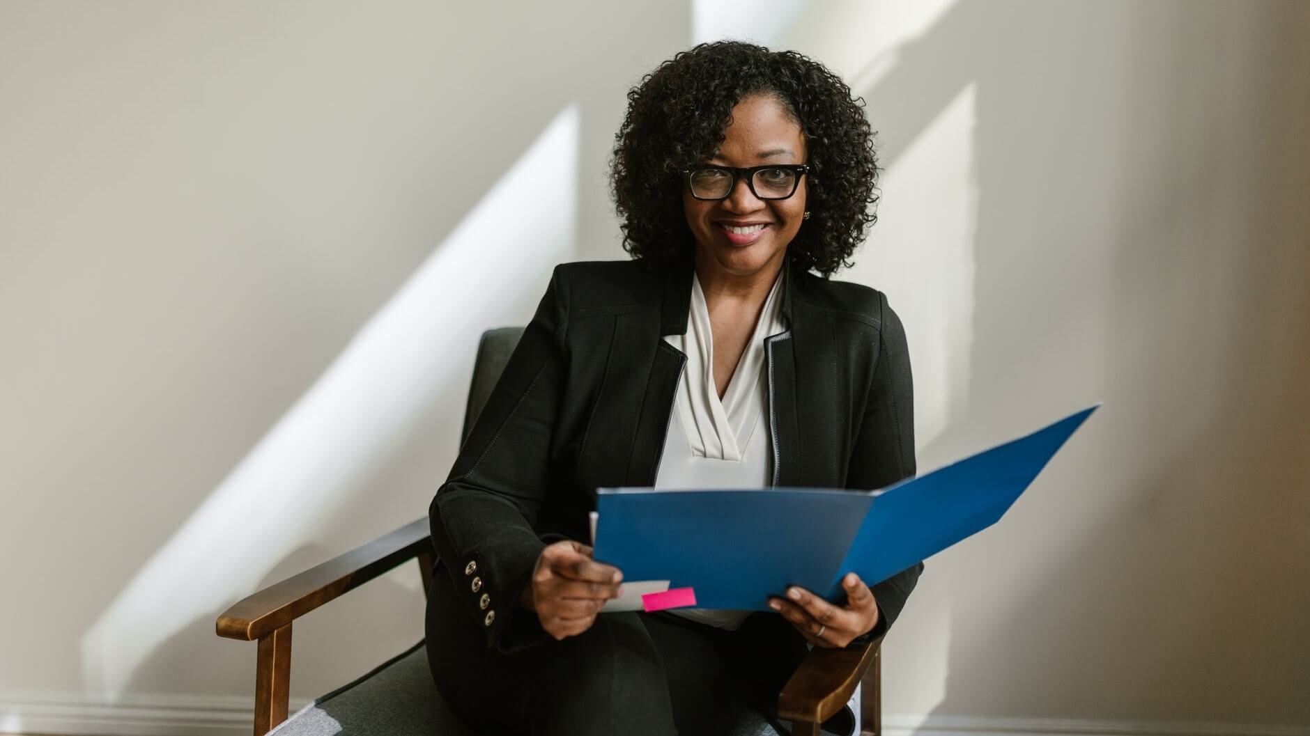 a woman smiling at the camera while holding a blue folder