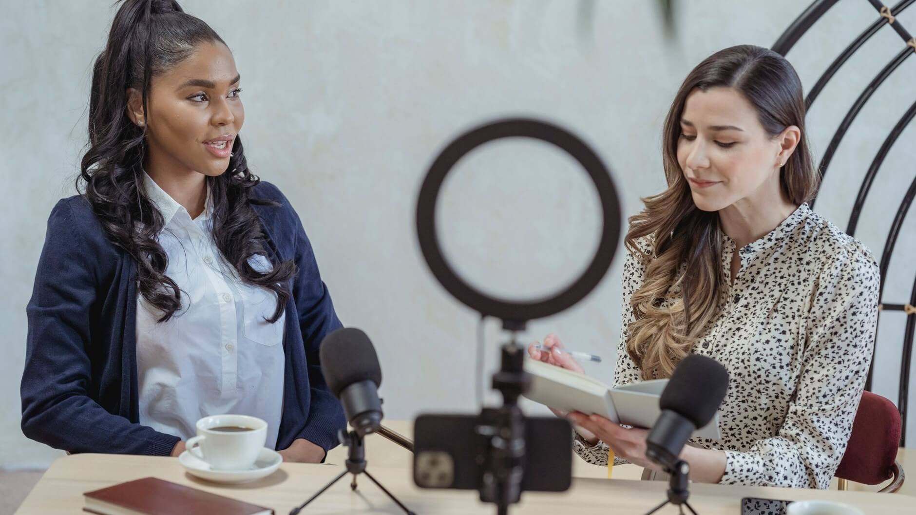 two women talking in front of a recording setup