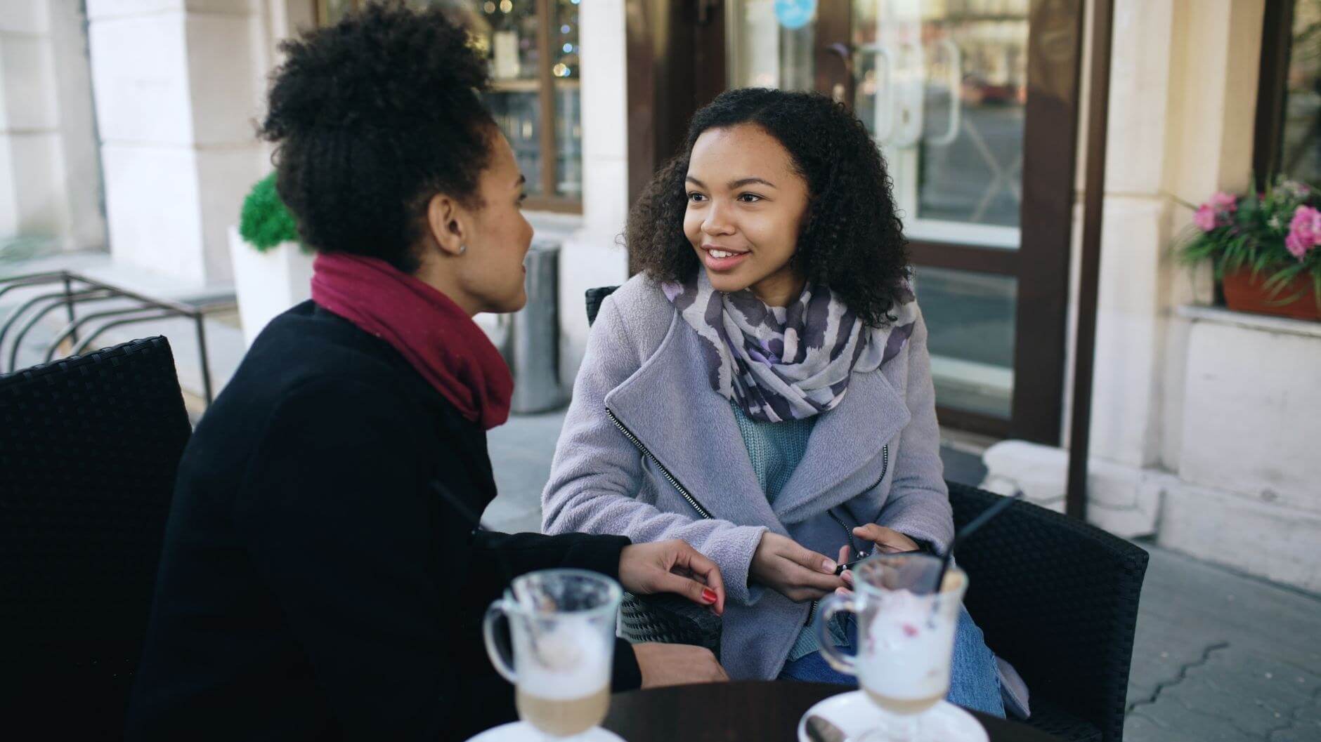 two women talking while drinking some beverage