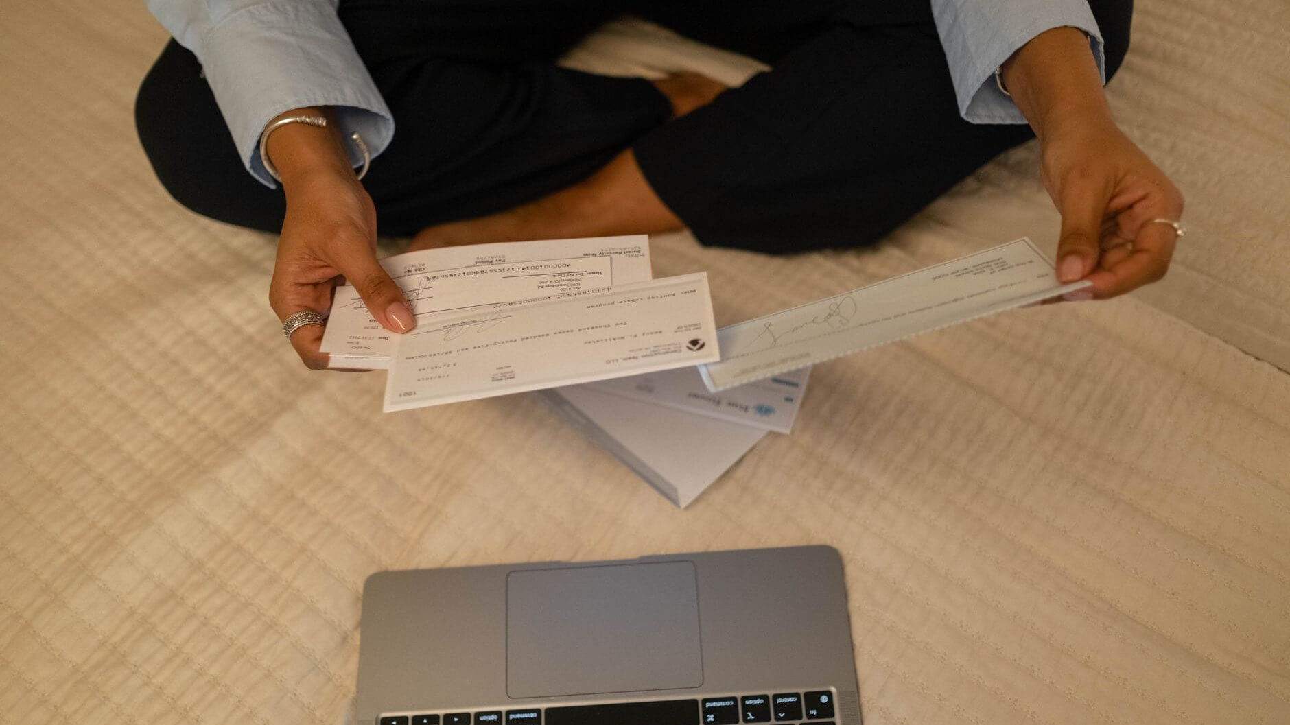 hands holding bills while in front of a computer