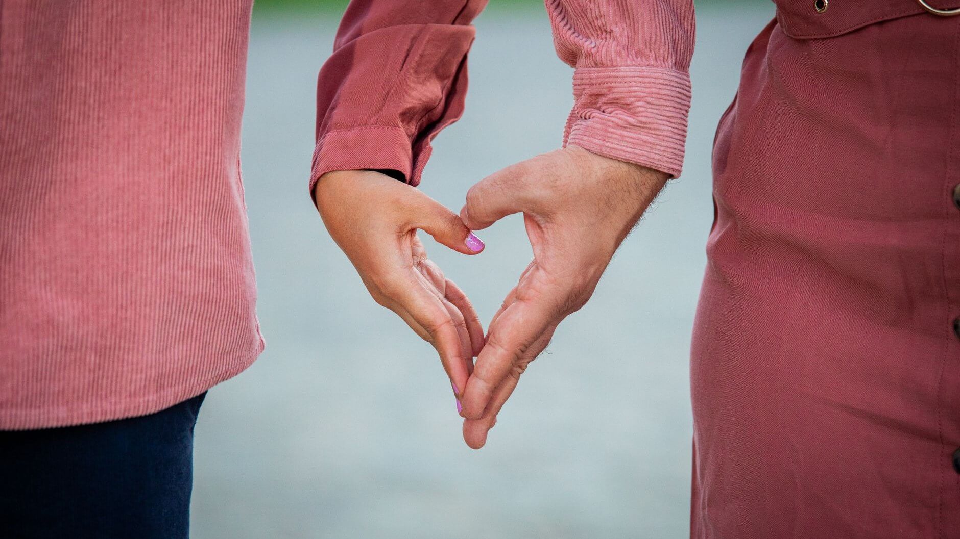 two hands intertwined forming a heart together
