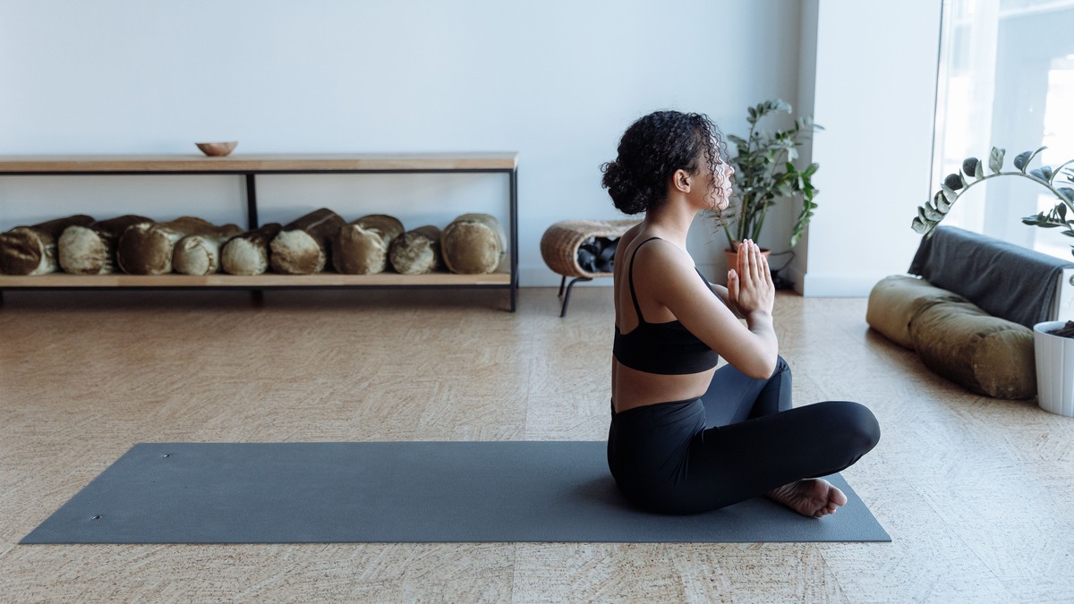 Woman practicing mindful breathing while seated on a yoga mat indoors