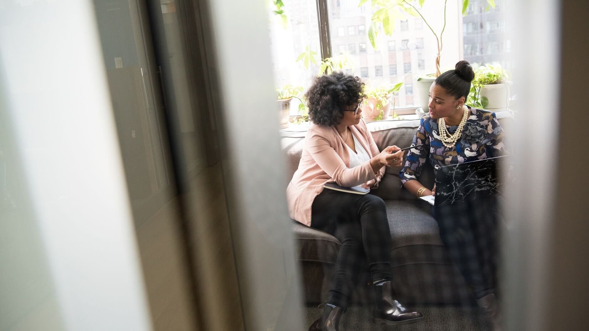 two women sitting in a couch talking