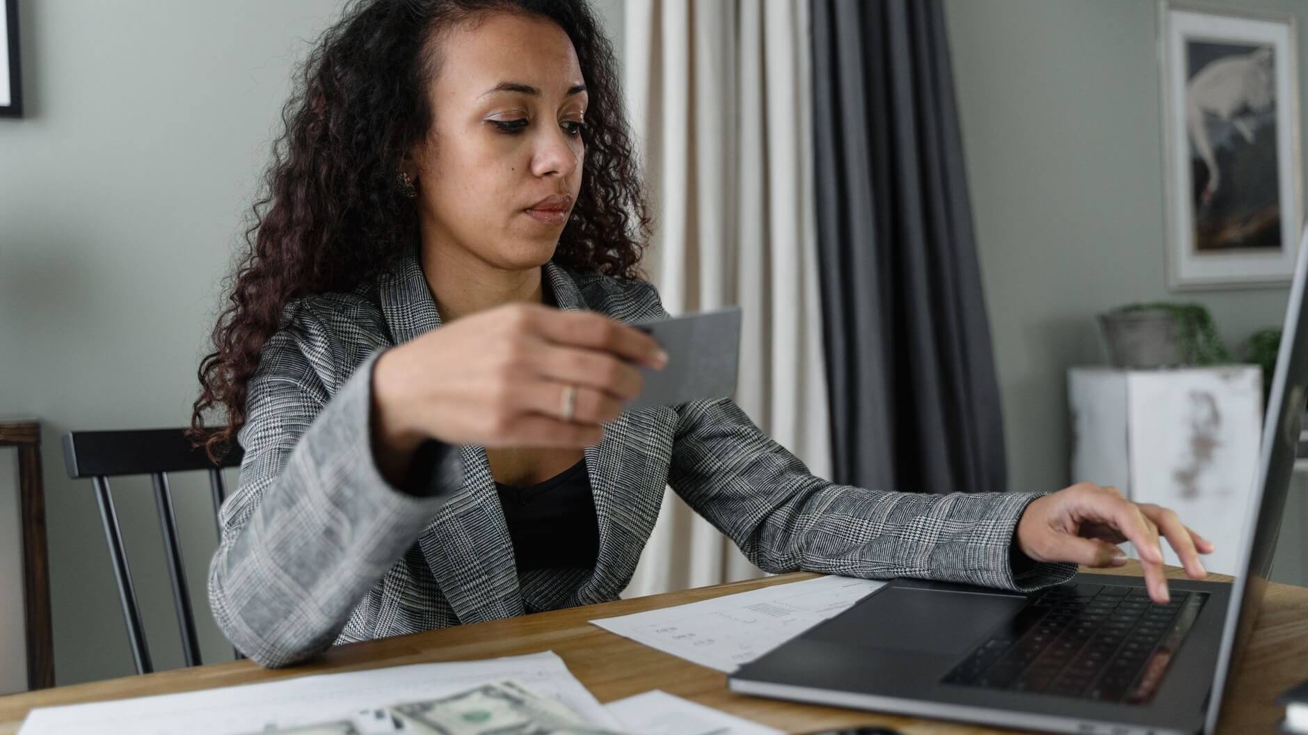 a woman using her laptop while holding a card