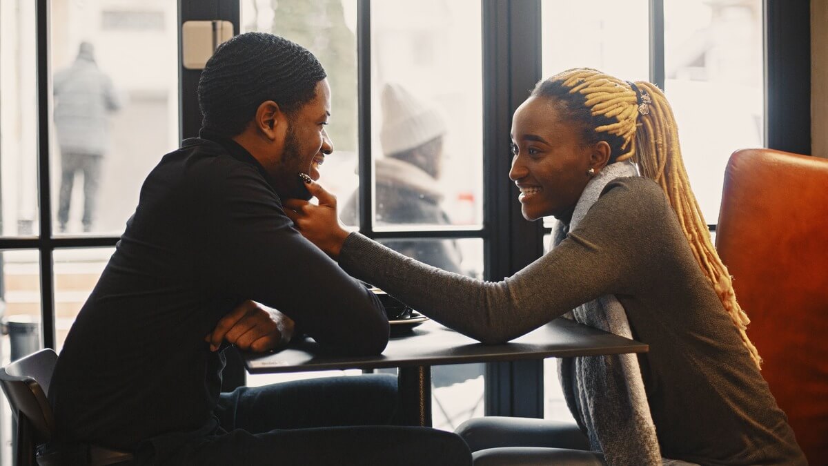 a woman touching a man on his chin inside a restaurant