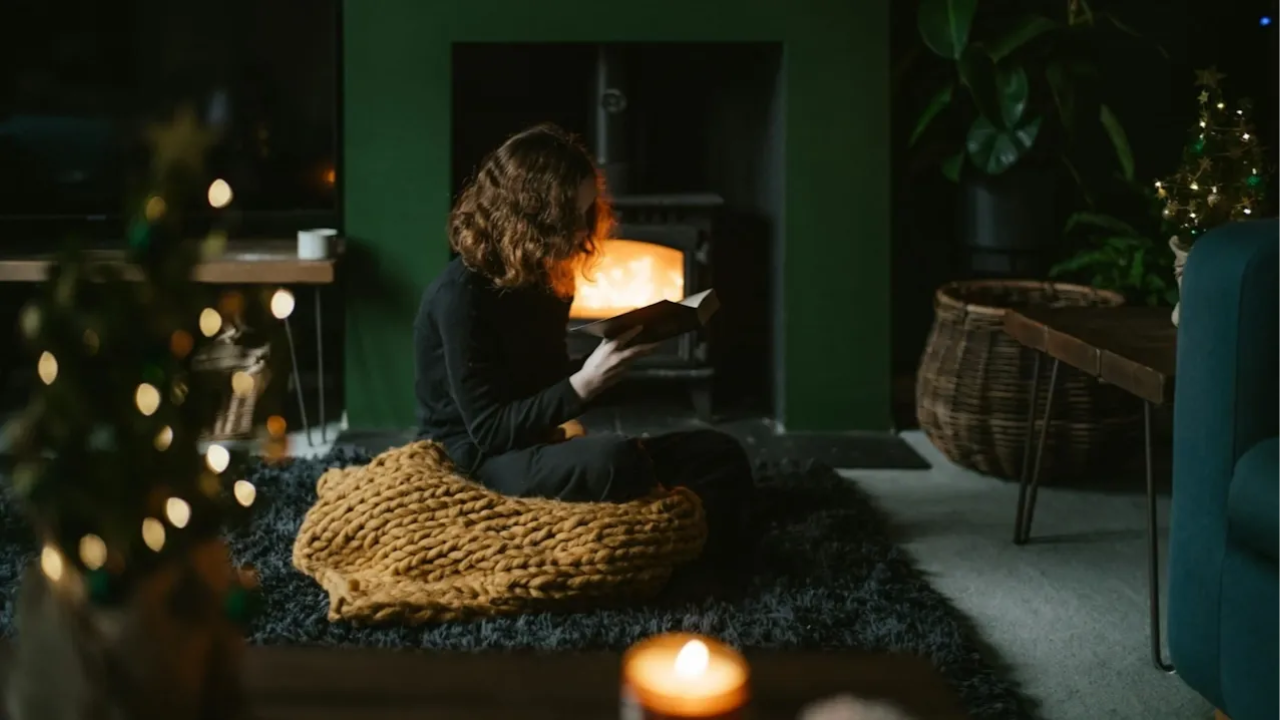 girl sat in living room reading as she relaxes during Christmas