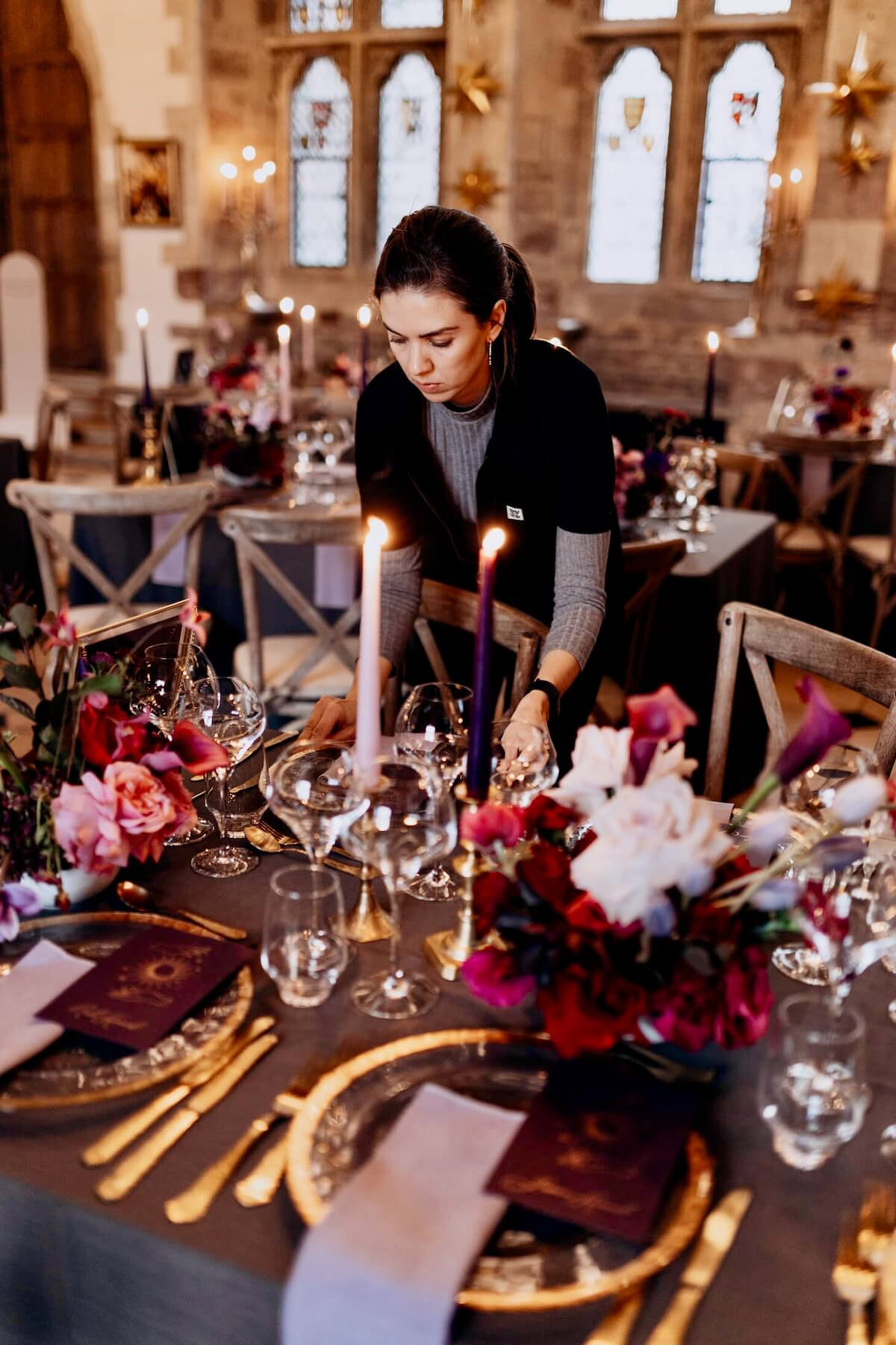 Amy Lord styling a candlelit banquet table with pink and burgundy flowers for an event design project