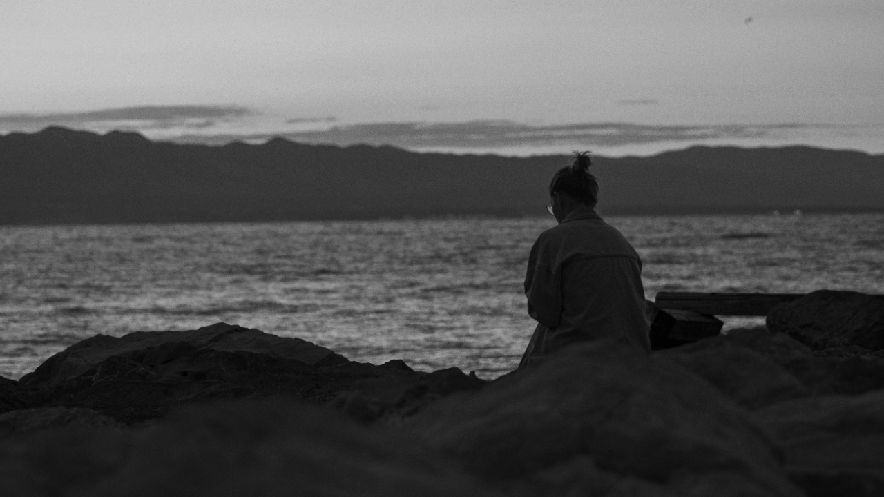 Woman sitting by the sea thinking.