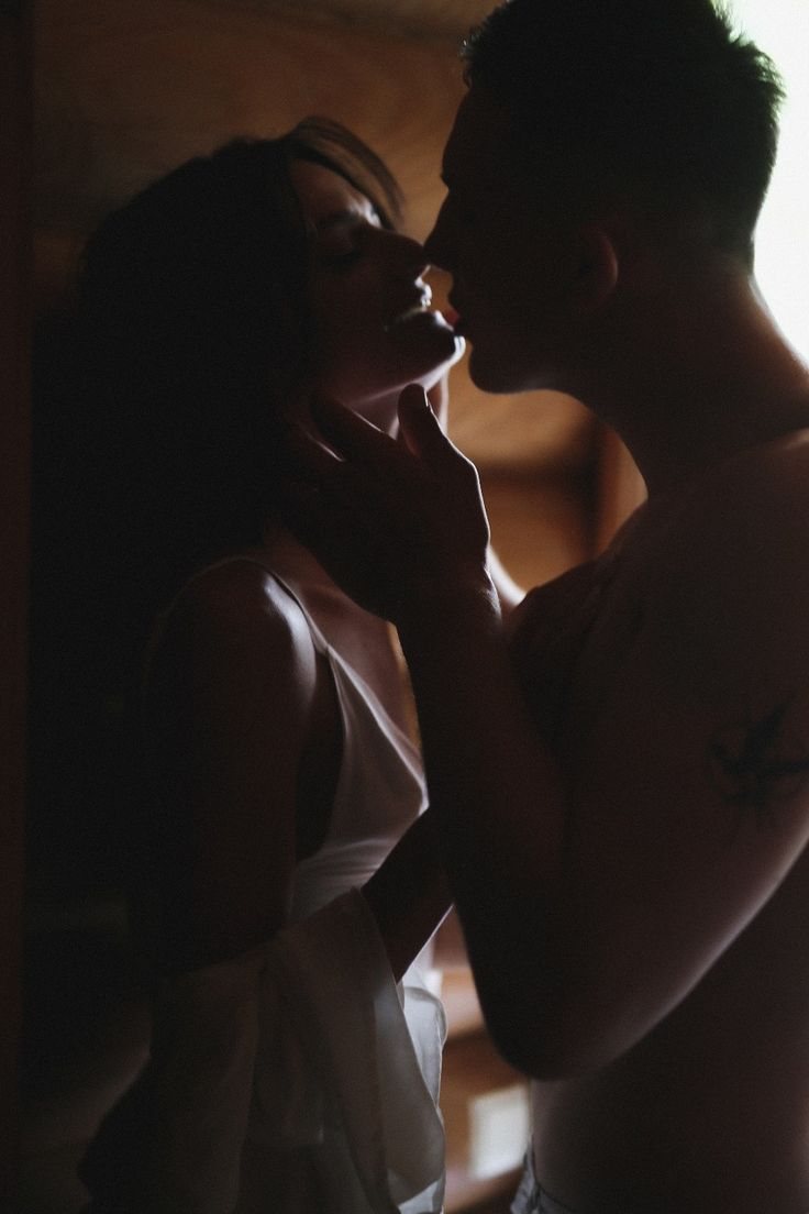 A silhouetted couple a breath away from a kiss, his hand gently cradling her jaw