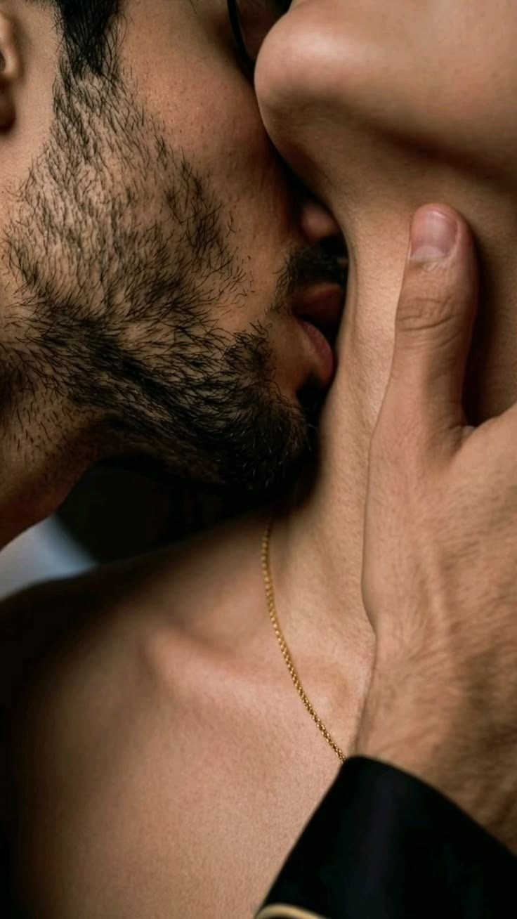 A bearded man presses a slow kiss to the side of a woman's neck as she leans into him