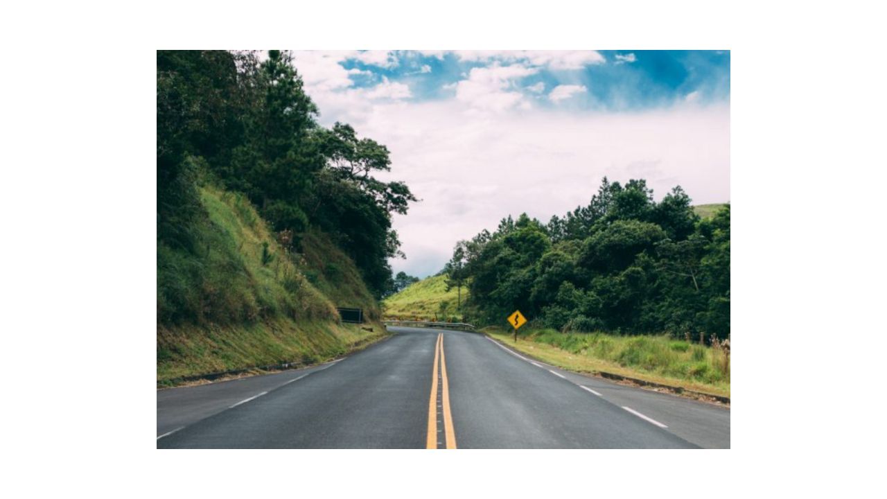 A gray highway runs into the horizon, framed by green hills and trees. It gives you a sense of momentum and moving forward.