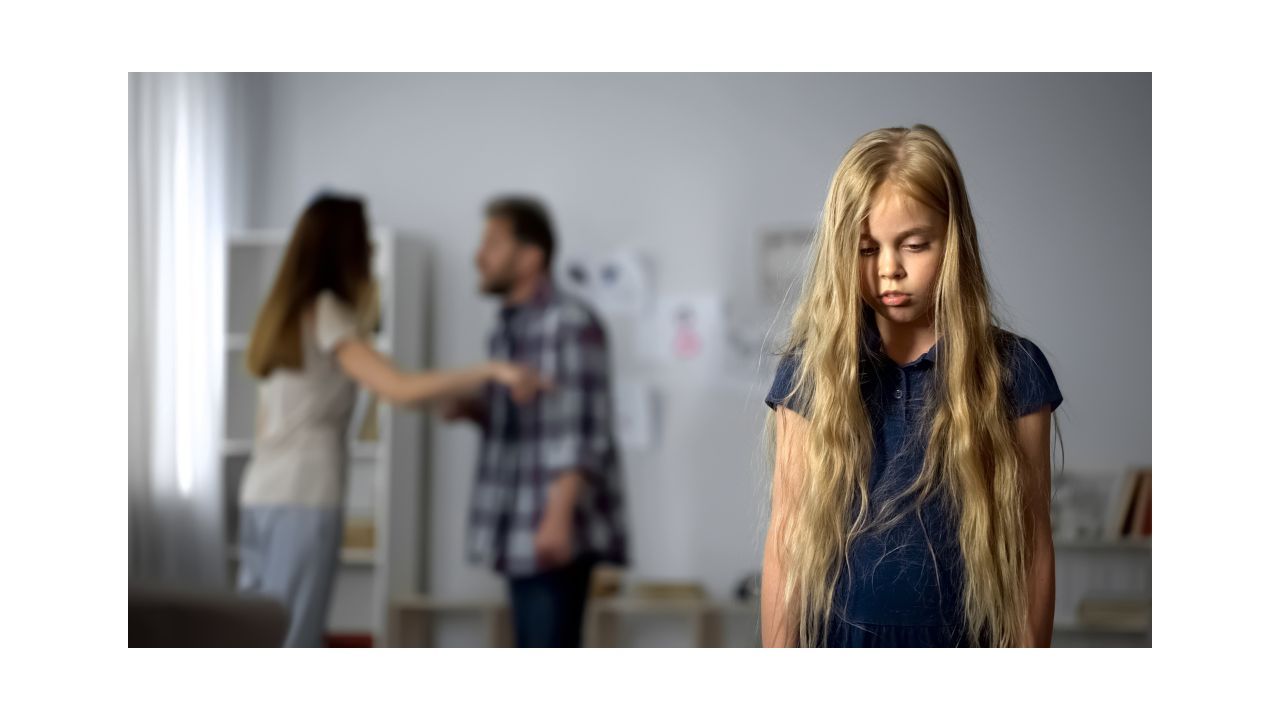 A child stands in the foreground with long hair partially obscuring her face. She is looking down as if she is scared or feeling ashamed. Two adults are arguing in the background and one has their hand held out to the other as if she is pushing him away.